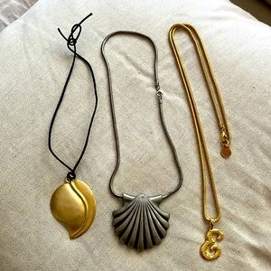 Three gold and silver pendant necklaces: gold E, silver shell and gold leaf.